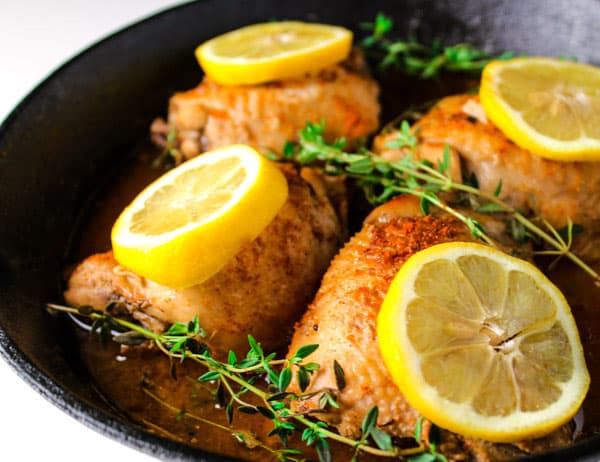 chicken thighs in a skillet with lemons