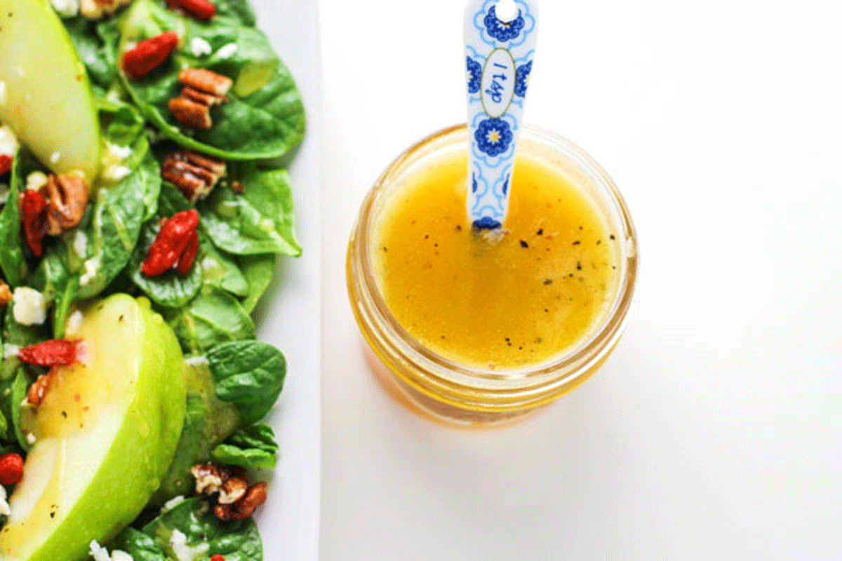 Apple Cider Vinaigrette in a jar next to a salad