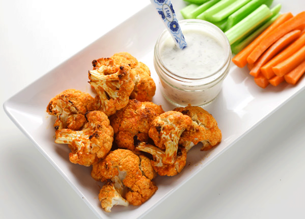 Buffalo cauliflower on a plate with ranch dressing, carrots and celery