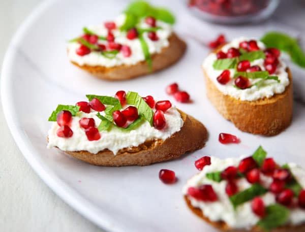 This Pomegranate Crostini with Ricotta and Mint will be your new favorite appetizer! It's super easy to make for any last minutes guests, and is sure to wow a crowd!