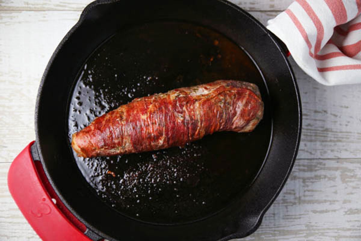 cooking prosciutto wrapped pork tenderloin in skillet