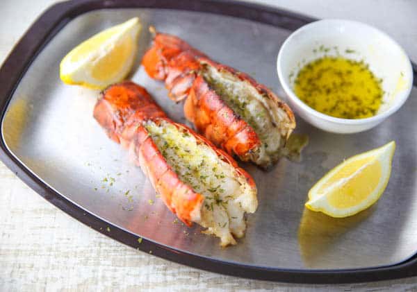 lobster tails oon a platter with lemon and butter