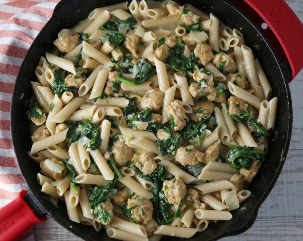 creamy chicken sausage and spinach pasta in a skillet