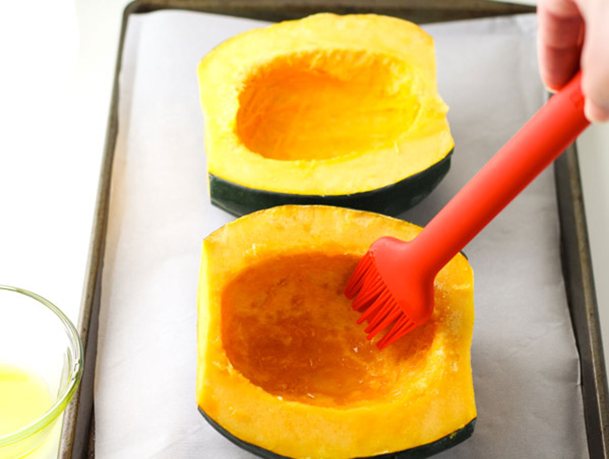 brushing inside of acorn squash with olive oil