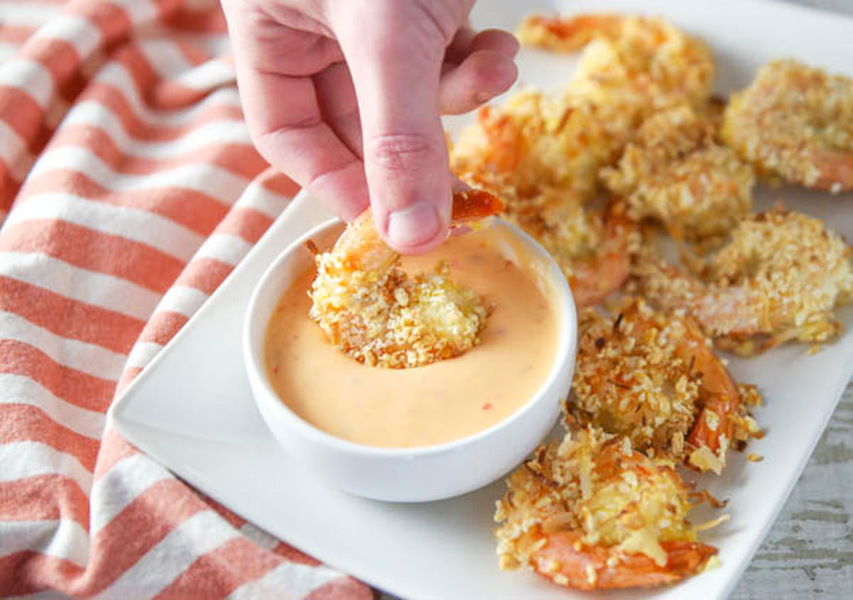 dipping coconut shrimp in spicy mayo