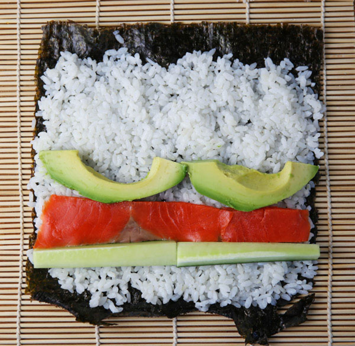 sushi rice on seaweed paper with avocado, smoked salmon and cucumber